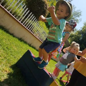 little preschool boy jumping off gymnastics foam wedge on grass